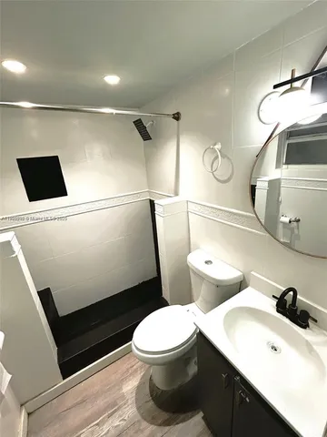 a white toilet sitting next to a bathroom sink and vanity