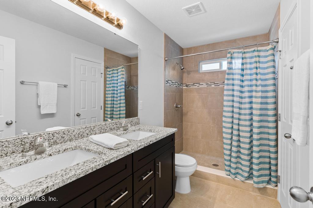 1330 Ellis Road South Jacksonville, FL 32205 - Photo 20 of 23 a bathroom with a granite countertop sink toilet and shower
