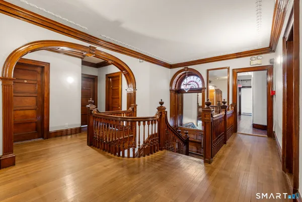 a view of a hallway with wooden floor and couches