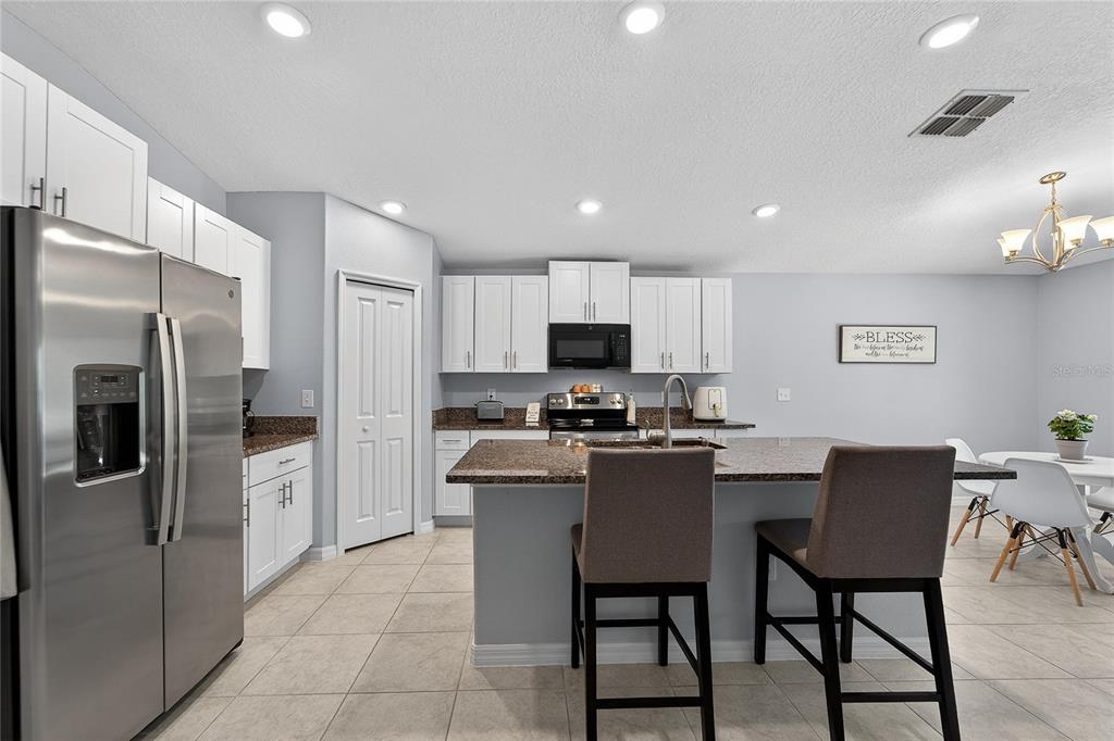 1728 Fred Ives Street Ruskin, FL 33570 - Photo 29 of 78 a kitchen with stainless steel appliances granite countertop a refrigerator a stove a sink a table and chairs