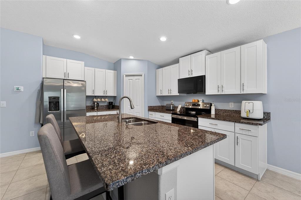 1728 Fred Ives Street Ruskin, FL 33570 - Photo 30 of 78 a kitchen with stainless steel appliances granite countertop a sink refrigerator and microwave