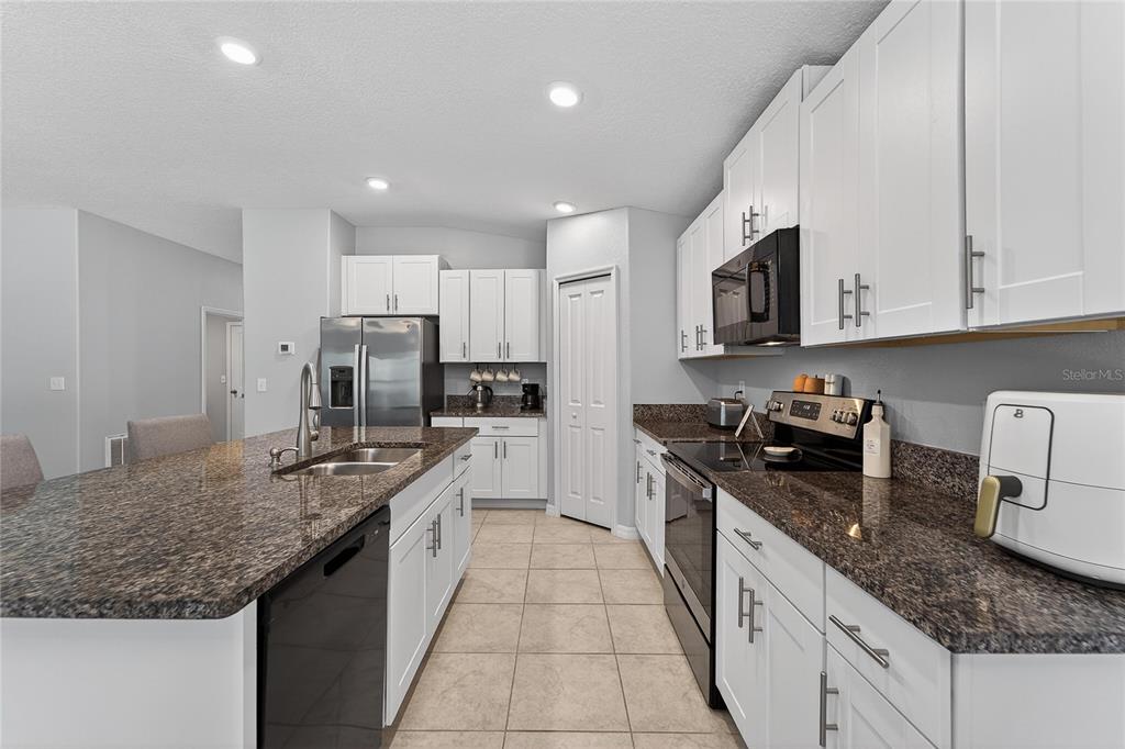 1728 Fred Ives Street Ruskin, FL 33570 - Photo 31 of 78 a large kitchen with stainless steel appliances granite countertop a sink stove and refrigerator