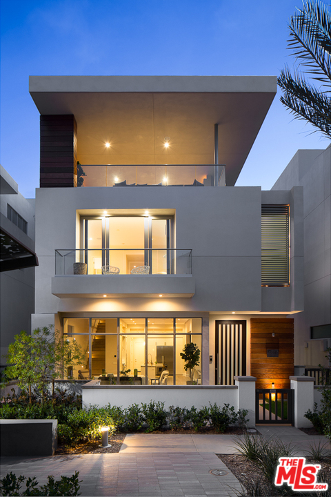 a front view of a building with lots of trees and plants