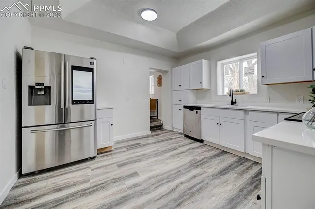 a kitchen with stainless steel appliances granite countertop a refrigerator sink and white cabinets