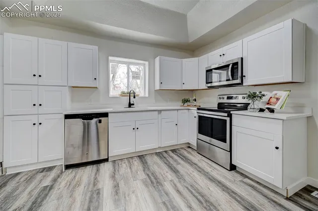 a kitchen with white cabinets stainless steel appliances and sink