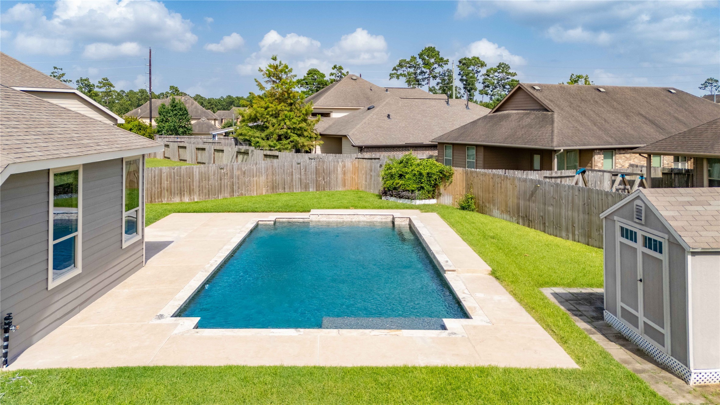 17206 Upper Ridge Lane Humble, TX 77346 - Photo 2 of 50 This backyard features a spacious in-ground pool surrounded by a clean patio area and a well-maintained lawn. It offers privacy with a wooden fence and includes a storage shed, providing a perfect space for relaxation and entertainment.