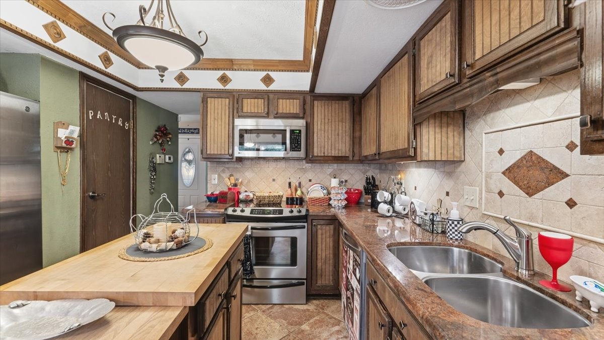 18 Still Glen Court Spring, TX 77381 - Photo 11 of 40 Nestled beyond the family room, you will find this quaint cooks paradise. The countertops are granite, the backsplash is tile. The range is Electric and there are plenty of cabinets for storing your special pieces