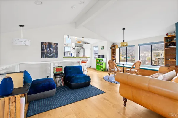 a kitchen with stainless steel appliances granite countertop a refrigerator a sink dishwasher a stove and a dining table with wooden floor