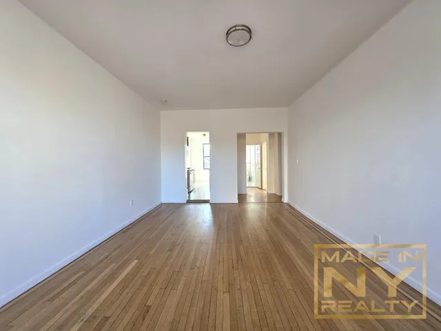 a view of an empty room with wooden floor and window