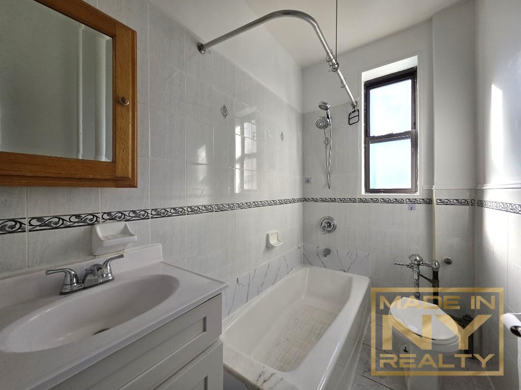 117-14 Union Turnpike, Unit BF1 Queens, NY 11415 - Photo 7 of 9 a bathroom with a tub sink and mirror