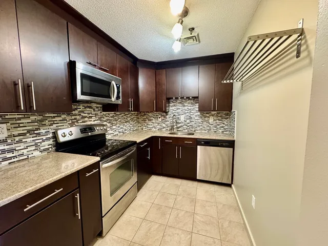 a kitchen with stainless steel appliances granite countertop a sink stove and microwave