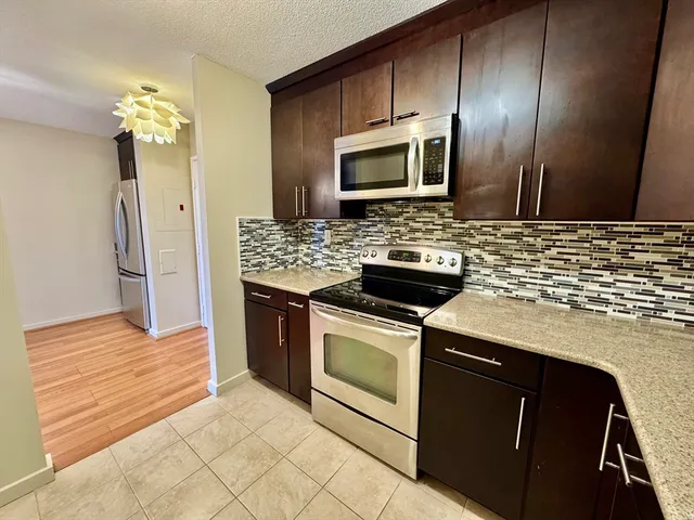 a kitchen with stainless steel appliances granite countertop a sink stove and microwave