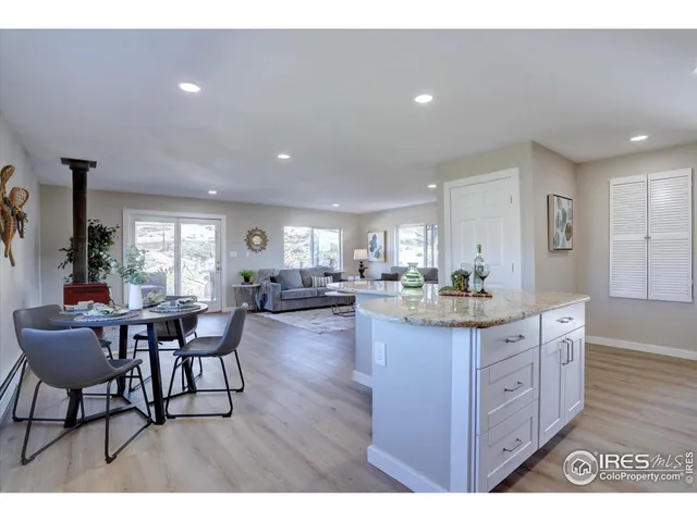 a kitchen with granite countertop a dining table chairs and wooden floor