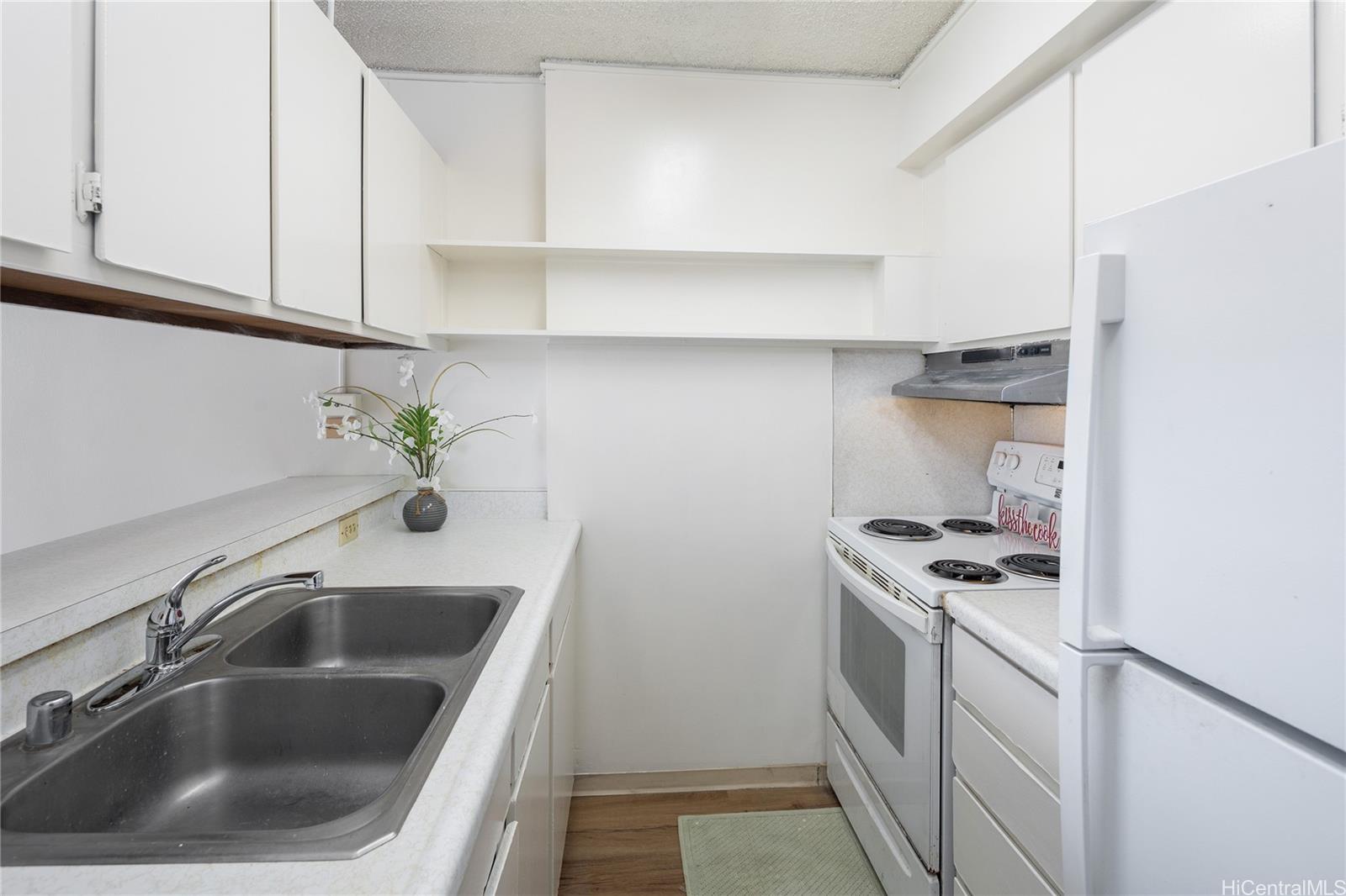98-450 Koauka Loop, Unit 1108 Aiea, HI 96701 - Photo 7 of 22 a kitchen with sink a stove and white cabinets
