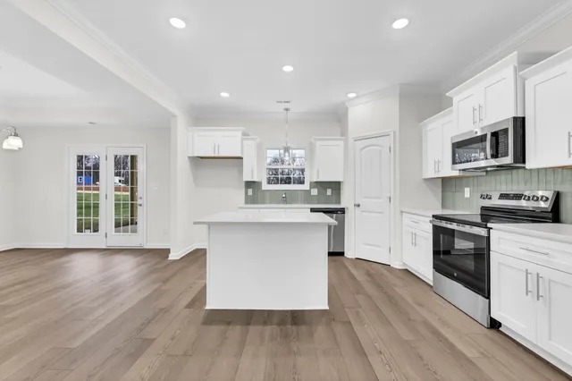 a kitchen with stainless steel appliances granite countertop a stove top oven a sink dishwasher and a refrigerator with wooden floor