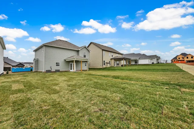 a view of a white house with a big yard and large trees