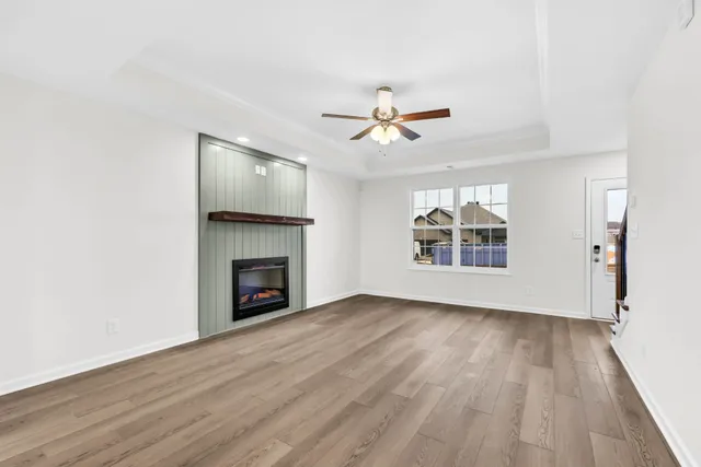 a view of an empty room with wooden floor fireplace and a window