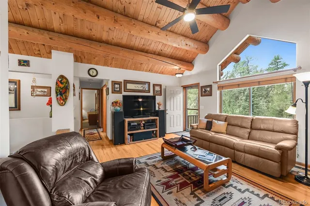 a living room with furniture a flat screen tv and a floor to ceiling window