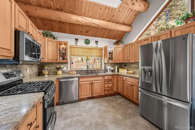 a kitchen with stainless steel appliances granite countertop a refrigerator a stove a sink and a microwave