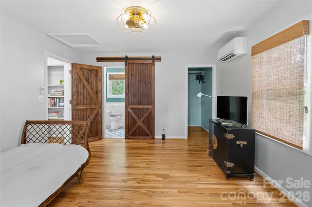 a bedroom with a bed and a flat tv screen on dresser
