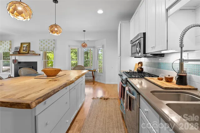 a kitchen with stainless steel appliances granite countertop a sink a stove and a wooden floors