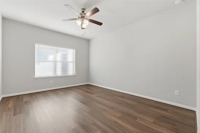 an empty room with wooden floor and ceiling fan