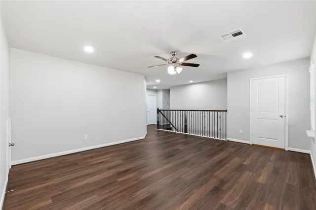a view of a room with wooden floor and a ceiling fan