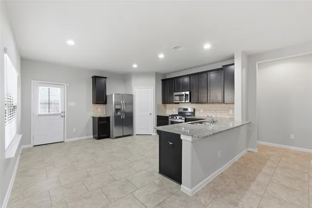 a large white kitchen with kitchen island granite countertop a sink and dishwasher a stove with wooden floor