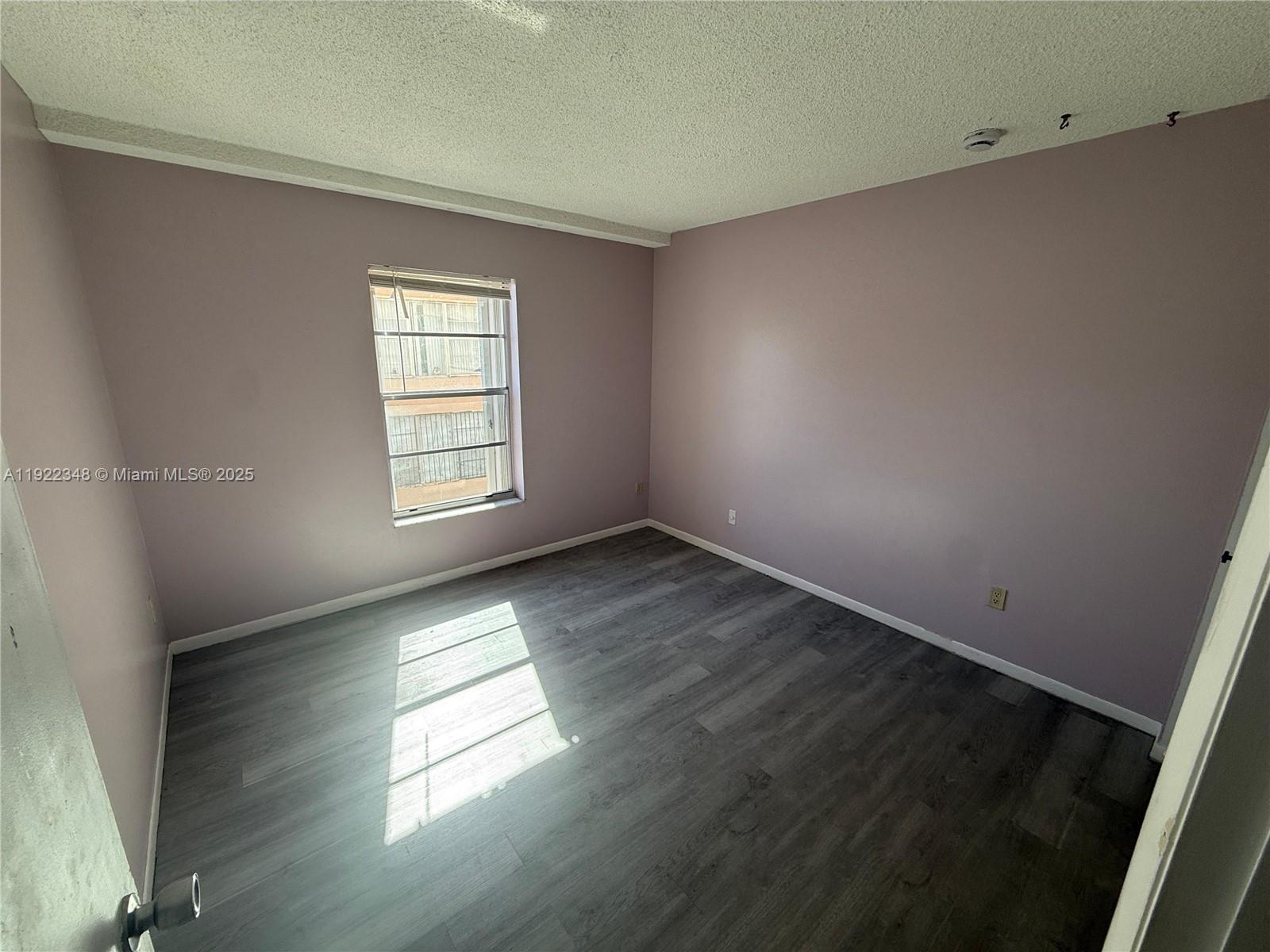 7355 West 4th Avenue, Unit 214 Hialeah, FL 33014 - Photo 8 of 15 an empty room with wooden floor and windows