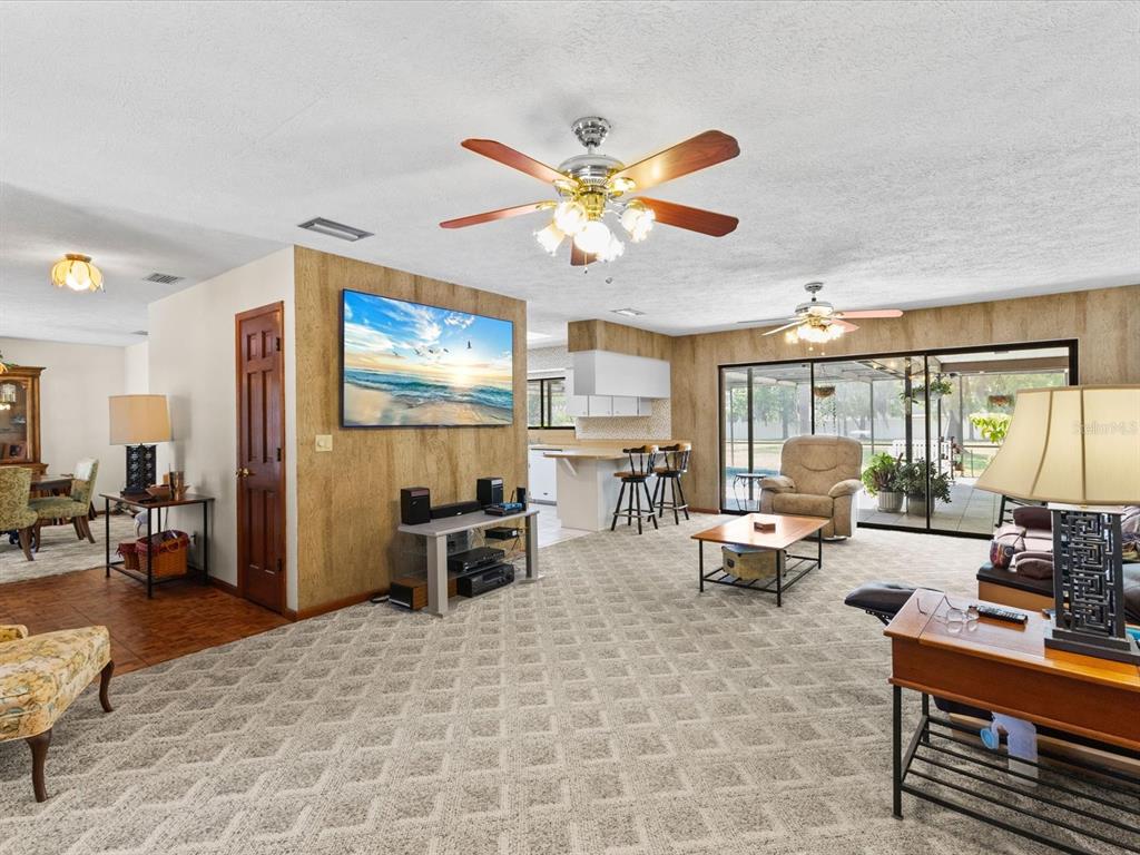 10700 Luscombe Court New Port Richey, FL 34654 - Photo 12 of 64 a living room with furniture a chandelier and a large window