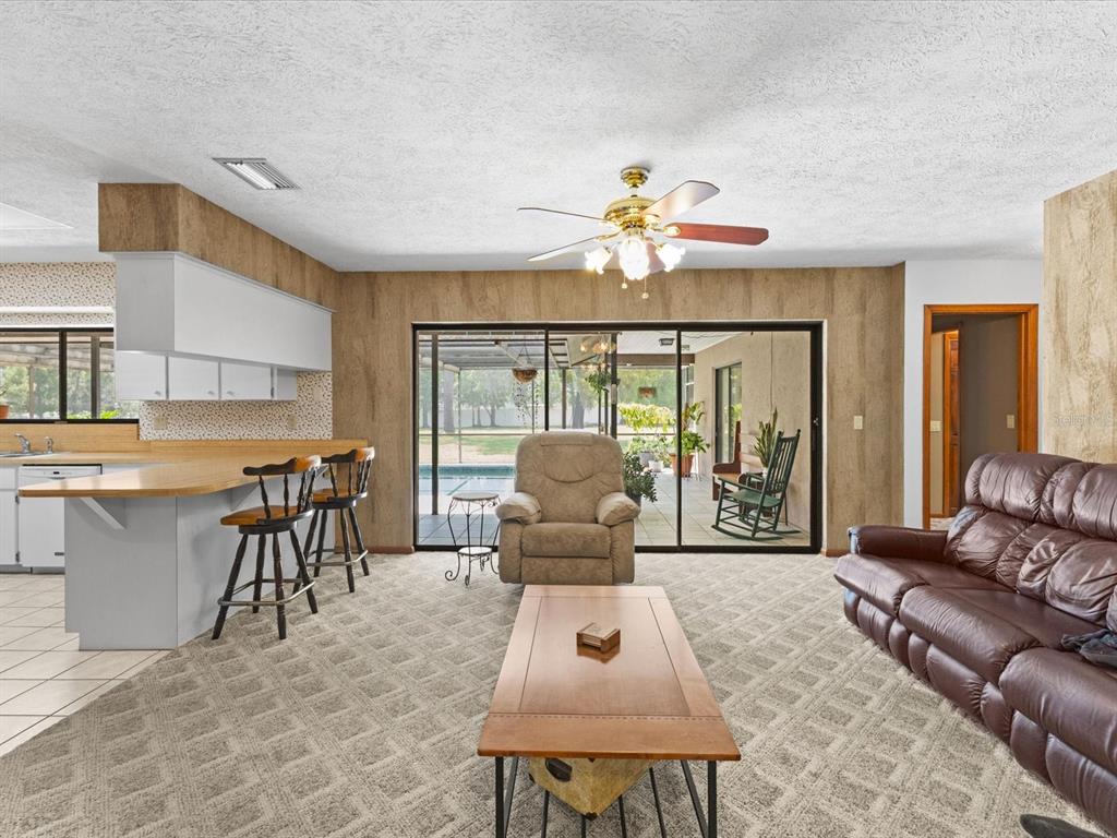 10700 Luscombe Court New Port Richey, FL 34654 - Photo 13 of 64 a living room with furniture a chandelier and a large window