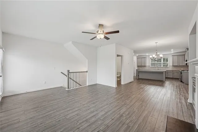 a view of an empty room with wooden floor and a ceiling fan