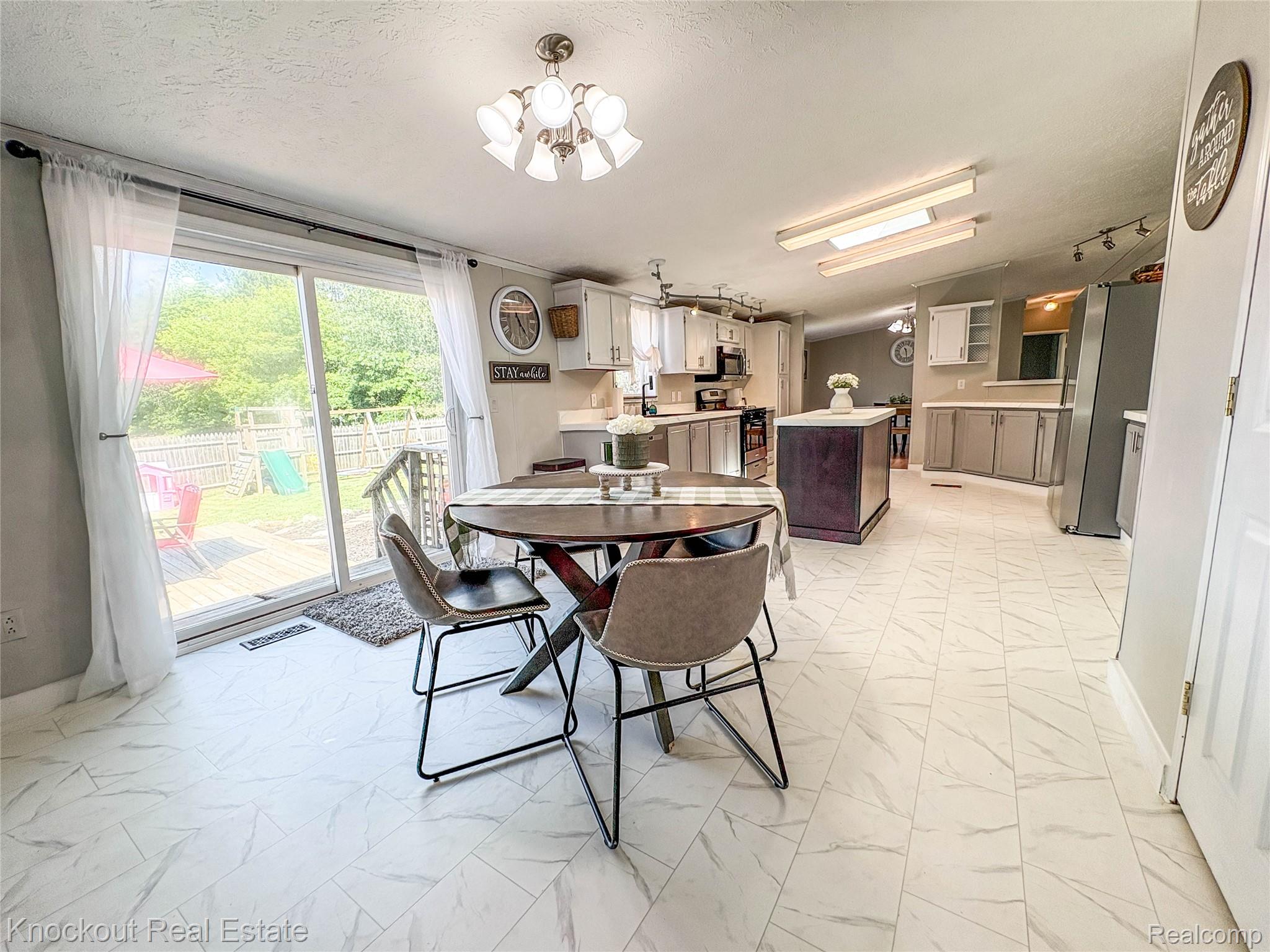 7760 Bell Road Birch Run, MI 48415 - Photo 22 of 68 Kitchen and dining area featuring light-toned flooring, a central kitchen island with a dark base, and light-colored cabinetry