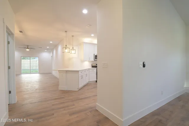 a kitchen with stainless steel appliances granite countertop a refrigerator a sink dishwasher a stove and white countertops with wooden floor