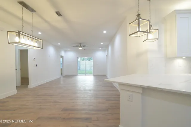 a view of an empty room and a kitchen