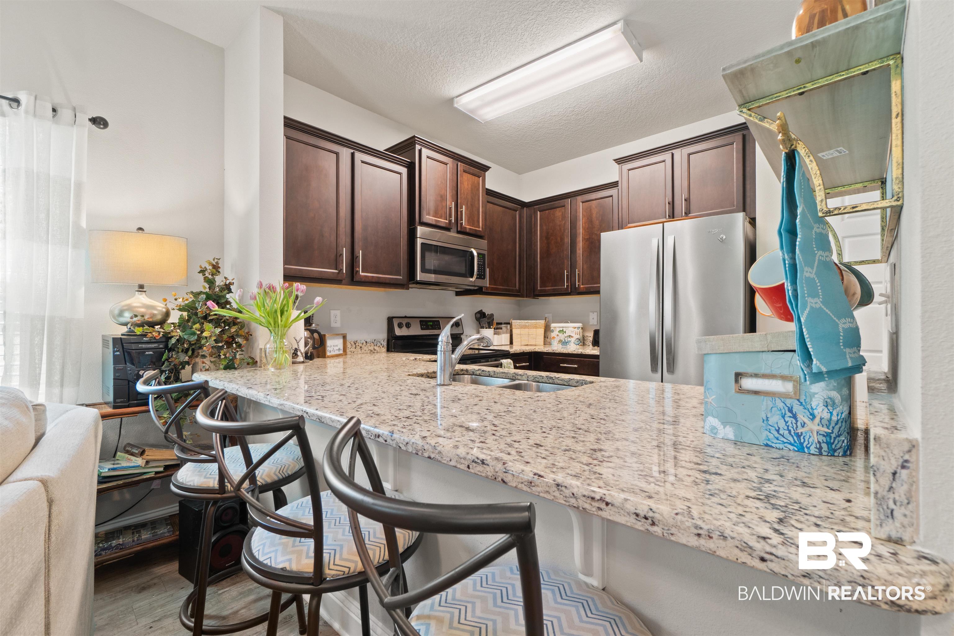 25806 Pollard Road, Unit 6 Daphne, AL 36526 - Photo 7 of 38 Kitchen featuring a peninsula breakfast bar with granite countertops and stainless steel appliances