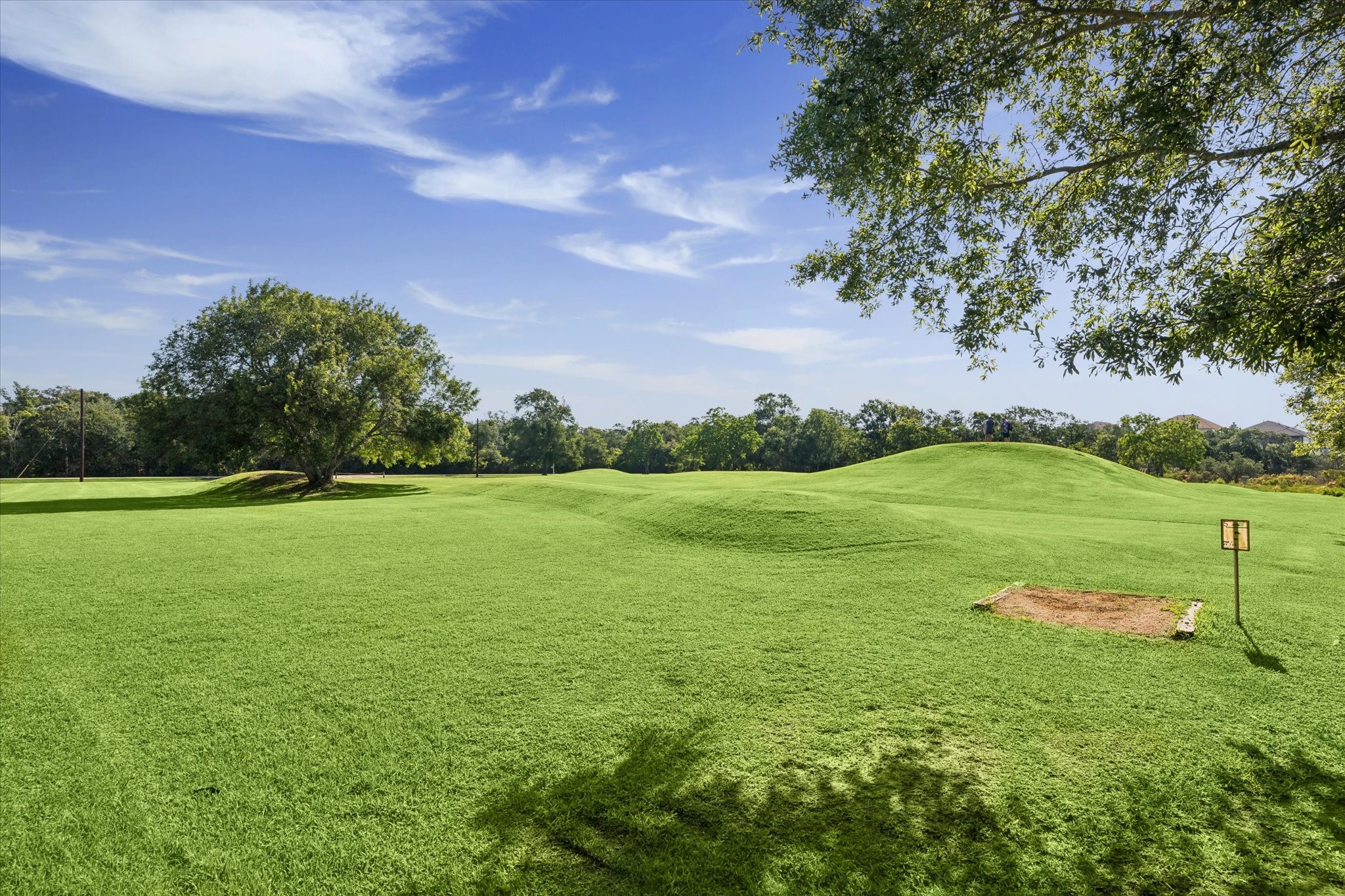 0 Hester Street Seabrook, TX 77586 - Photo 11 of 16 Expansive, lush green landscape with gentle hills and mature trees under a clear blue sky, ideal for outdoor activities and enjoying nature.