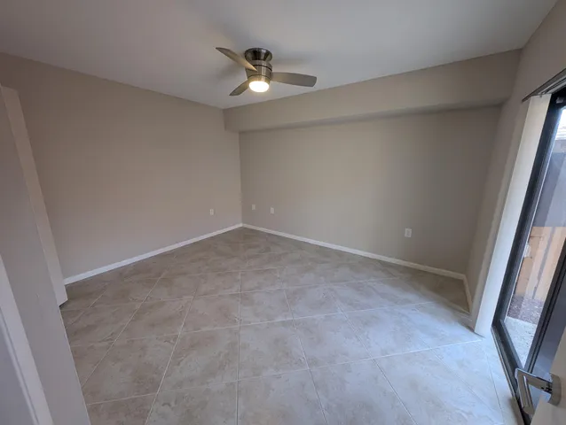 an empty room with a chandelier fan and windows
