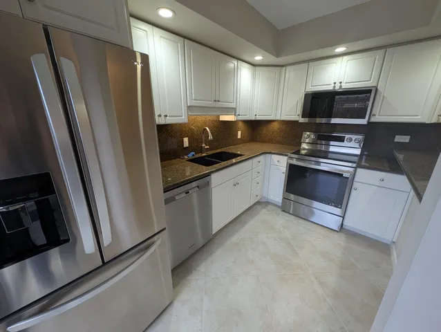a kitchen with stainless steel appliances a refrigerator a sink a stove a microwave and cabinets