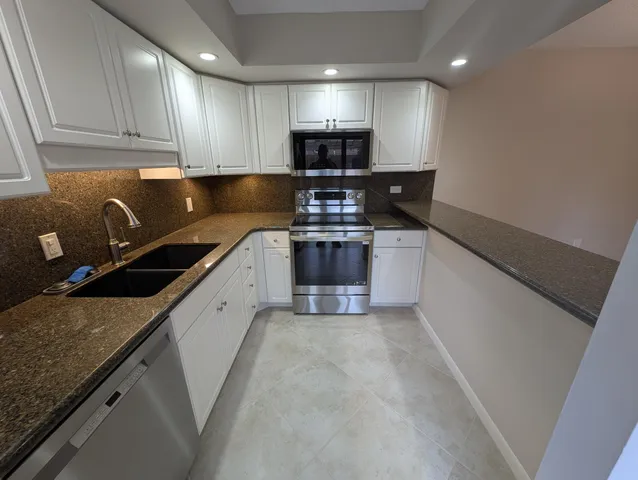 a kitchen with granite countertop a sink and a stove top oven