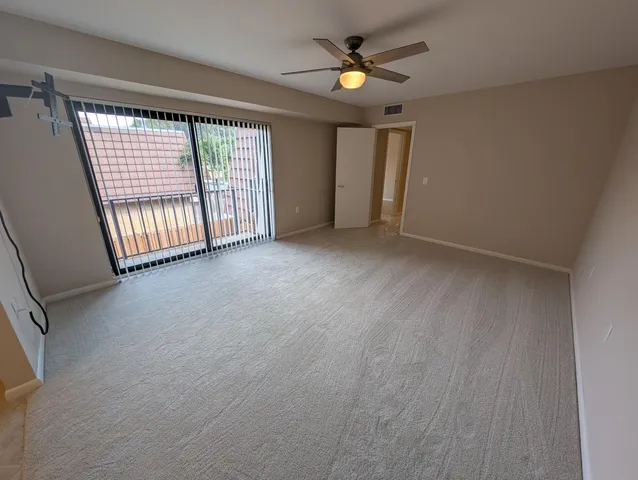 an empty room with windows and fan