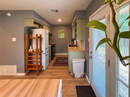 a view of a hallway with wooden floor and a bathroom