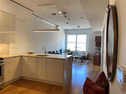 a kitchen with stainless steel appliances granite countertop a refrigerator a sink dishwasher a stove and white countertops with wooden floor