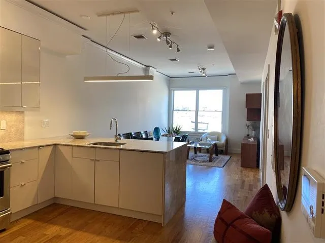 a kitchen with stainless steel appliances granite countertop a refrigerator a sink dishwasher a stove and white countertops with wooden floor