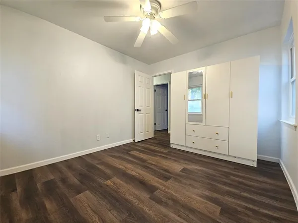 an empty room with wooden floor cabinet and windows