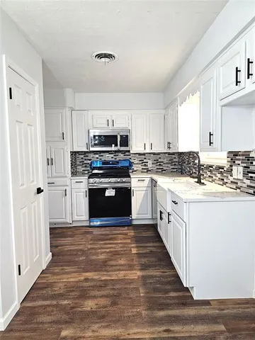 a large kitchen with cabinets stainless steel appliances and a window