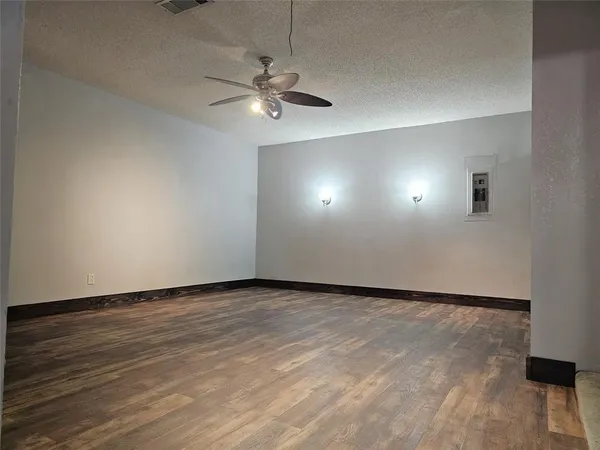 an empty room with wooden floor fan and windows
