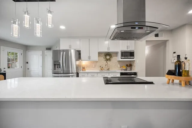 a large kitchen with stainless steel appliances a stove a sink dishwasher and a refrigerator with wooden floor