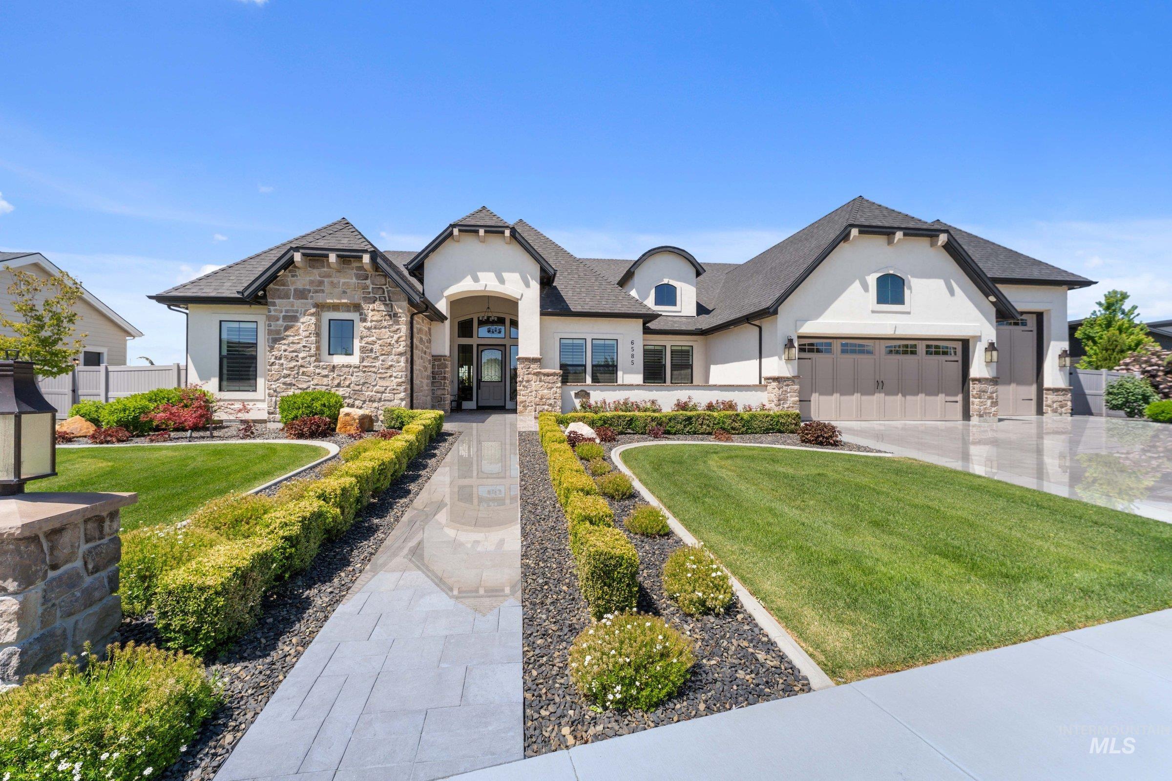 6585 South Pemberley Way Meridian, ID 83642 - Photo 2 of 43 Stucco and stone exterior featuring an arched entry, a multi-pane front door, and a spacious three-car garage