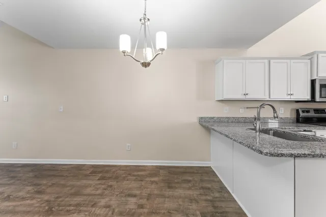 a kitchen with kitchen island granite countertop a sink a counter space and cabinets